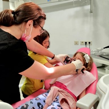 Fotografía intraoral para diagnóstico y seguimiento Odontóloga realiza fotografía intraoral a una niña con retractores mientras otra niña observa en Presencia Dental