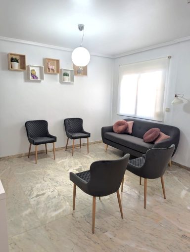 Sala de espera en Puçol (Puzol) Sala de espera de Presencia Dental en Puçol con sofá y sillas grises, luz natural y decoración minimalista