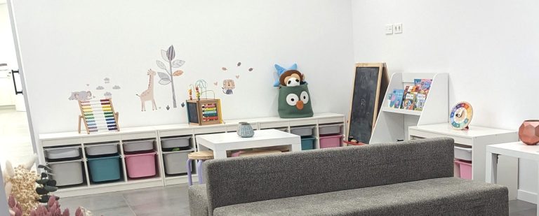 Zona infantil con libros y juegos Zona infantil en la sala de espera de Presencia Dental con libros, pizarra, ábaco y mesa baja